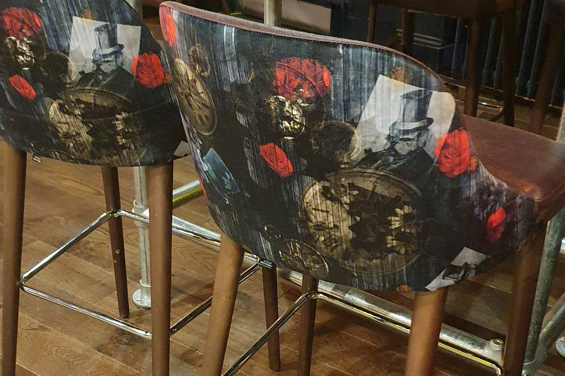 Dog N' Watch fabric design by ATADesigns and Arka Chergui upholstered on bar stools at The Priory.  The design features a british bulldog smoking a pipe and wearing a top hat among poppies, and pocket watch on a dark background.