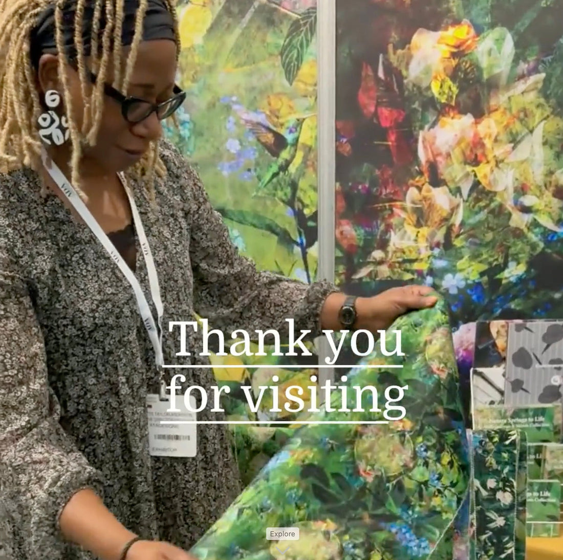 Annette Taylor-Anderson of ATADesigns on her stand looking at wallpaper at the Independent Hotel Show 2024.  Her stand is decorated with wallpaper.