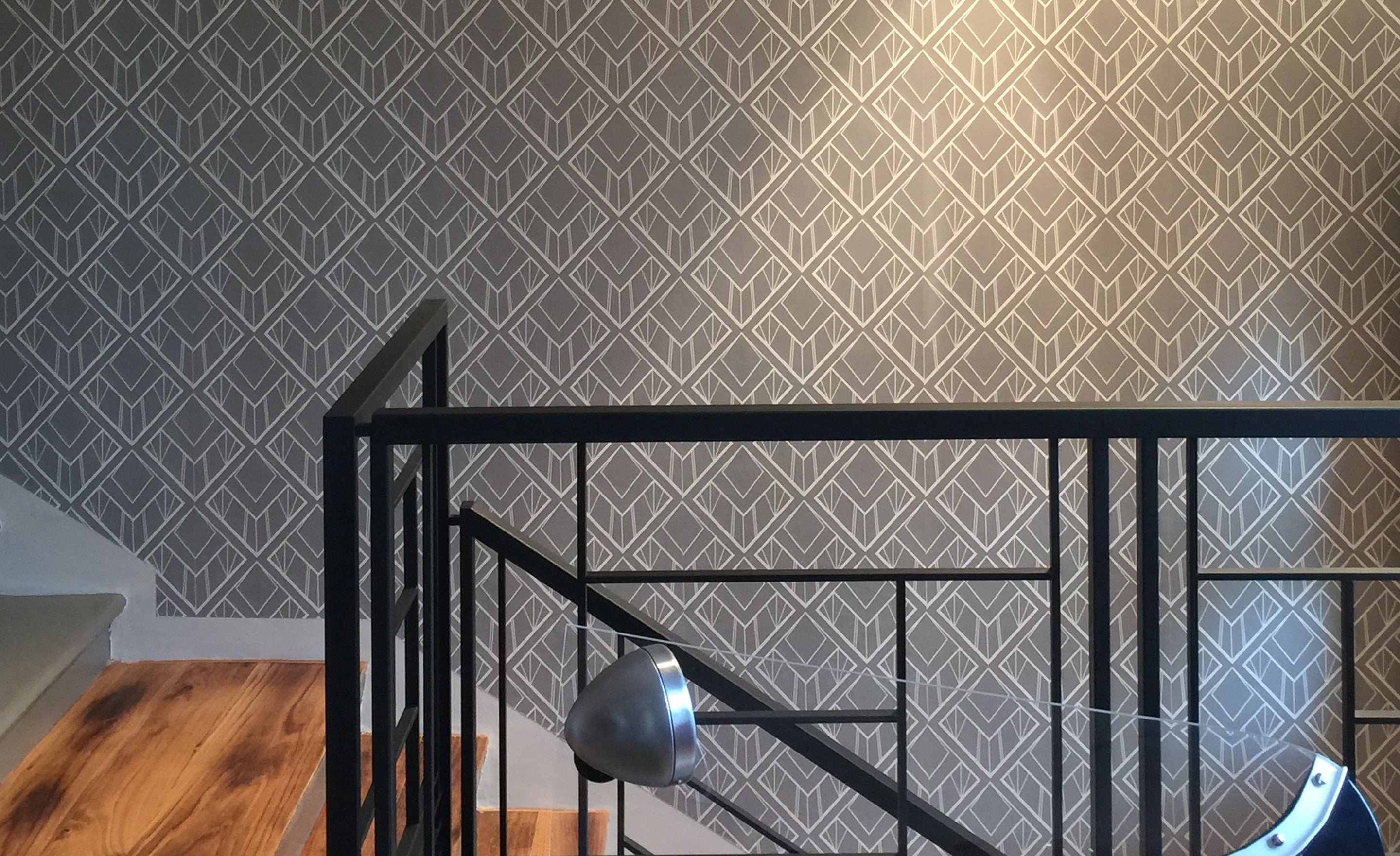 Diamond-cut wallpaper design by ATADesigns.  Featuring white diamond shapes illustration on light grey background installed in hallway wall by steps