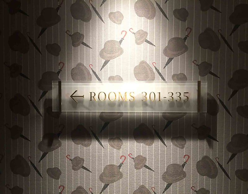 Close up of he Bowler wallpaper design by ATADesigns featuring Bowler hats and Umbrella's in repeat at The London Marriot Hotel.  Room numbers sign is fitted on the wall