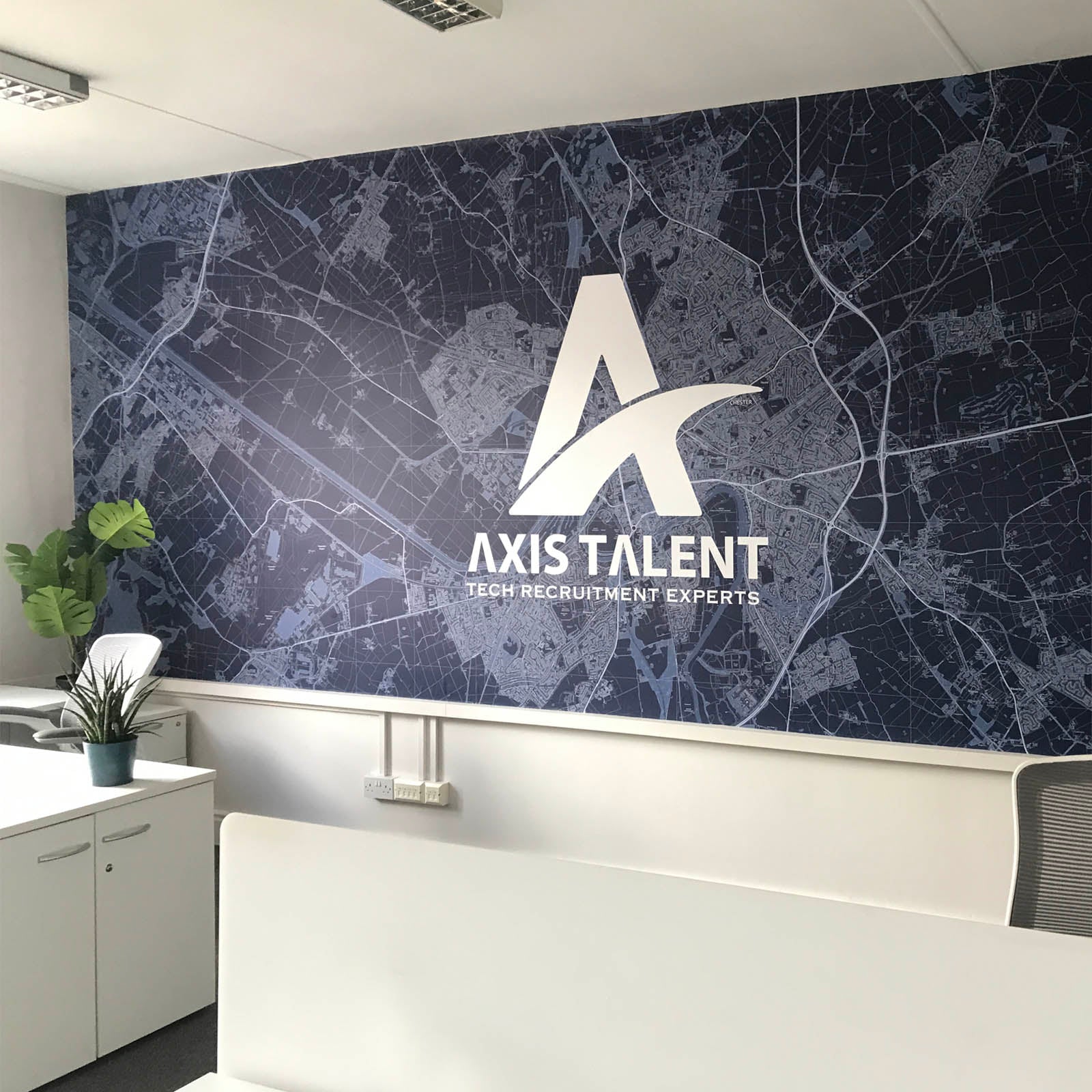 Office space with white desks featuring a map mural  colour in dark blue with Axis Talent giant logo incorporated in the map.