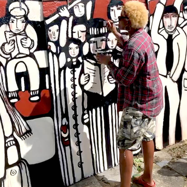 Person painting a mural with abstract human figures on a wall.  