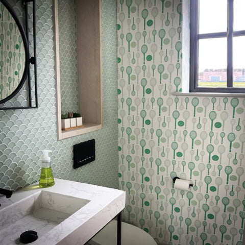 Bathroom features modern sink and small window, features green wallpaper and tennis racket and ball wallpaper around window.  Tennis racket and ball wallpaper by ATADesigns.
