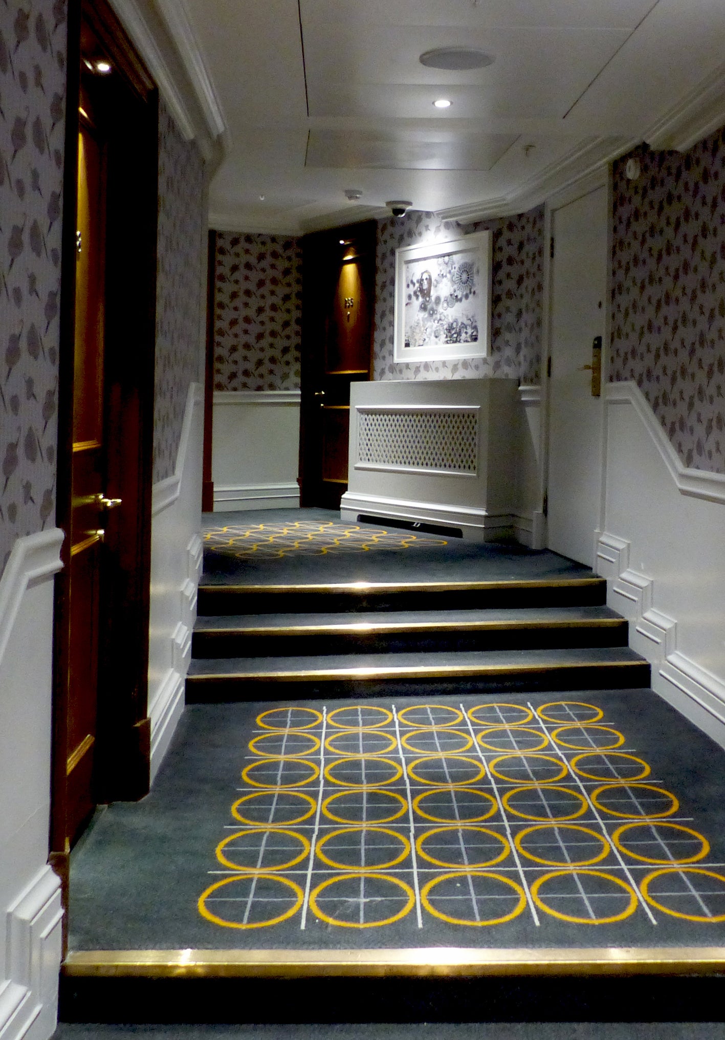 Staircase with decorative carpet and bowler hats wallpaper design by ATADesigns in a hallway at the London Marriott Hotel.