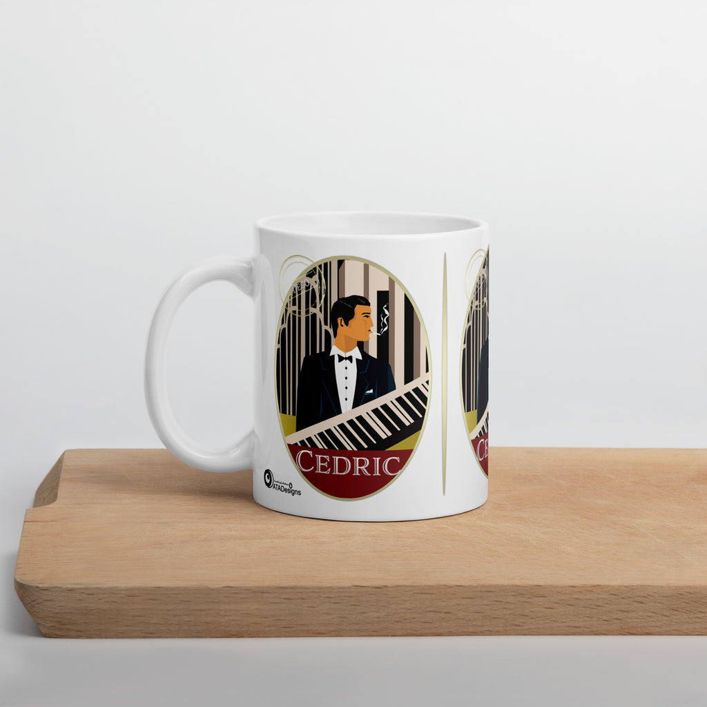 White Cedric Art Deco mug with a man in a dinner jacket and piano-key artwork, displayed on a wooden board.