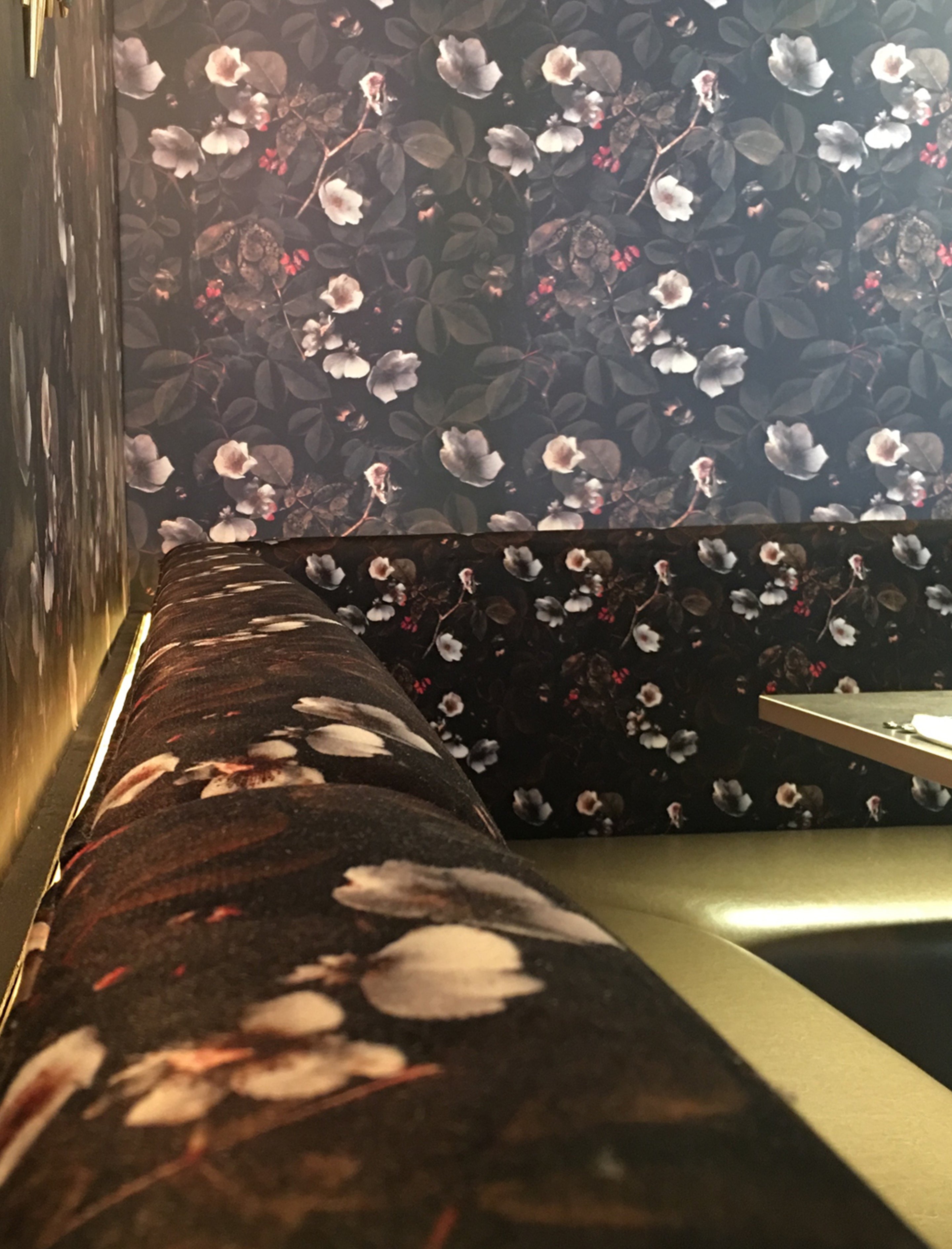 Close up of Kews Leafy Florals wallpaper and furnishing fabric design upholstered on to banquet seating in restaurant.
