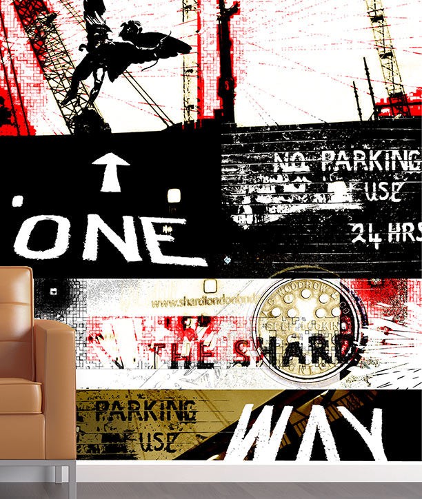 A modern abstract collage wall mural featuring distressed typography, a gold coin graphic, and a crane silhouette, shown in a room setting with a tan leather armchair on the left. One Way Mural design by ATADesigns.