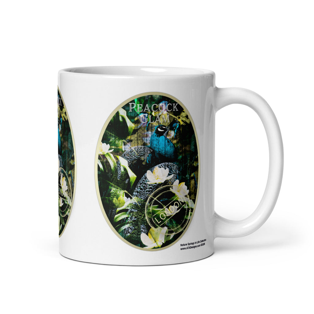 Peacock Glam mug by ATADesigns with a blue peacock, green foliage and white flowers, handle on the right.